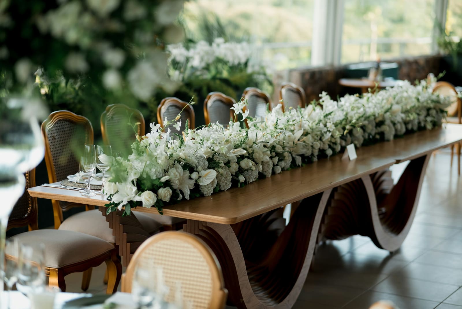 Long wooden reception table adorned with cascading white floral centerpieces
